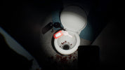 A white ceramic toilet with the lid open, shown in a dark bathroom scene with a flashlight beam illuminating the inside of the bowl and floor. A red-and-white handheld device rests on the rim, with a key on the toilet lid and blood-like splatters on the floor.
