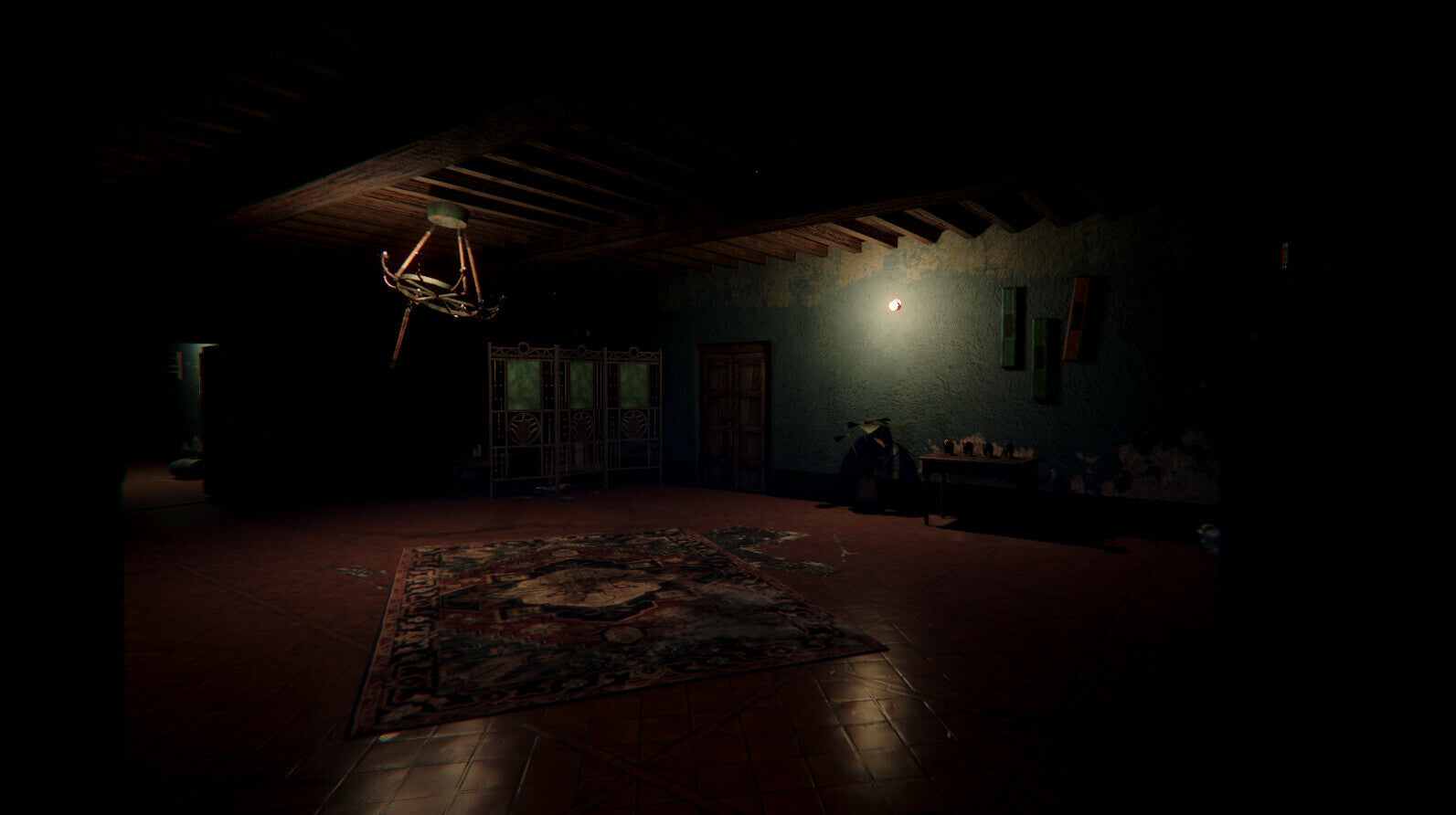 A dark, atmospheric interior room with a low hanging chandelier, a patterned rug on the floor, and a faint light source on the back wall.