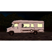 White RV with glowing windows in a dark forest setting
