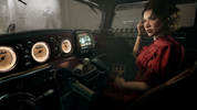 Woman sitting inside a vehicle with a dashboard filled with gauges and controls.