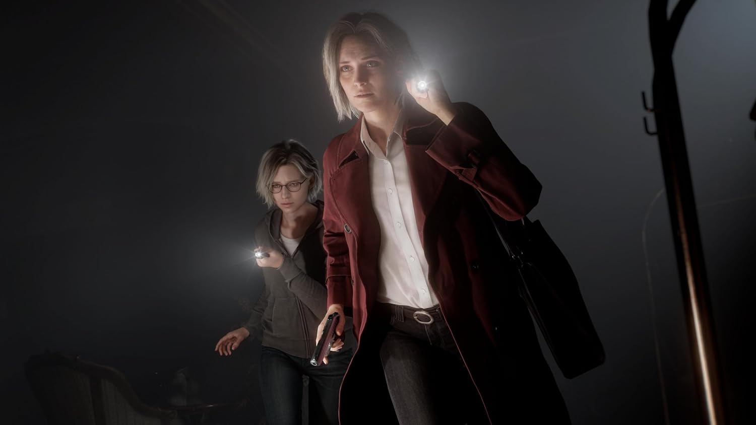 Two people in dark clothing with flashlights in a dimly lit setting