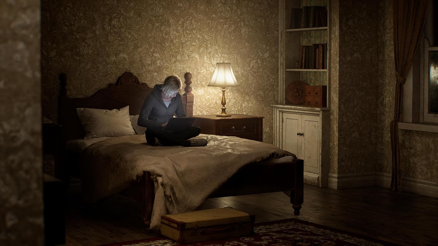 Person using a laptop in a dimly lit bedroom with patterned wallpaper and a lamp on a nightstand.