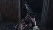 A close-up shot of a person's hands holding a black semi-automatic pistol in a dimly lit, rustic indoor setting.