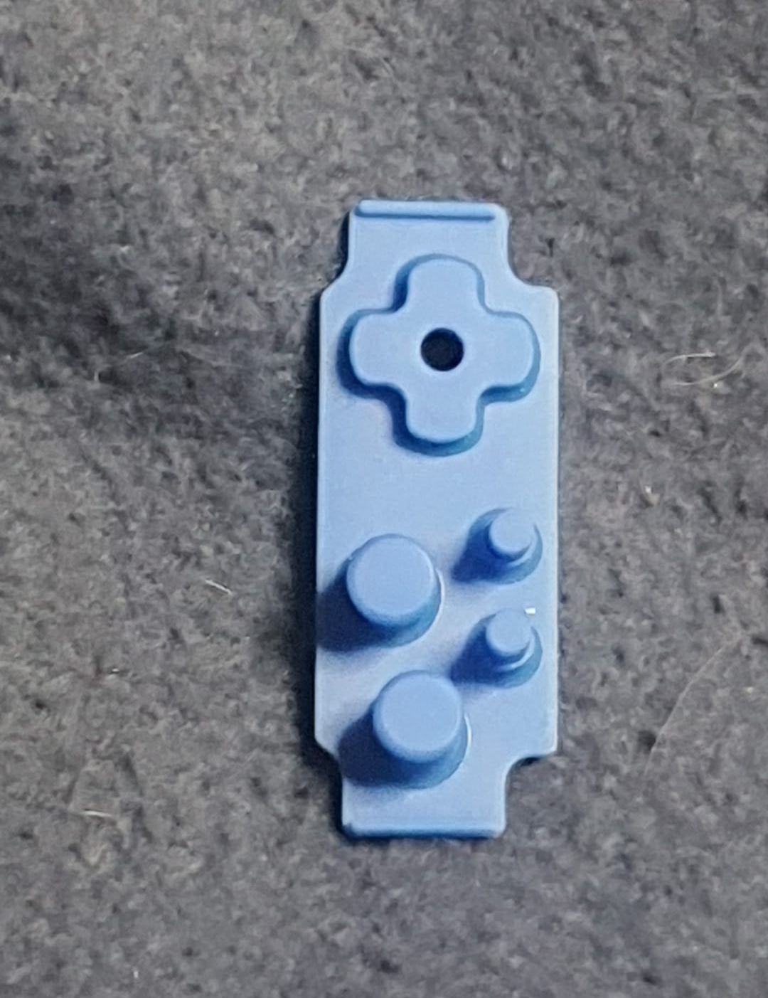 Blue plastic component on a gray surface