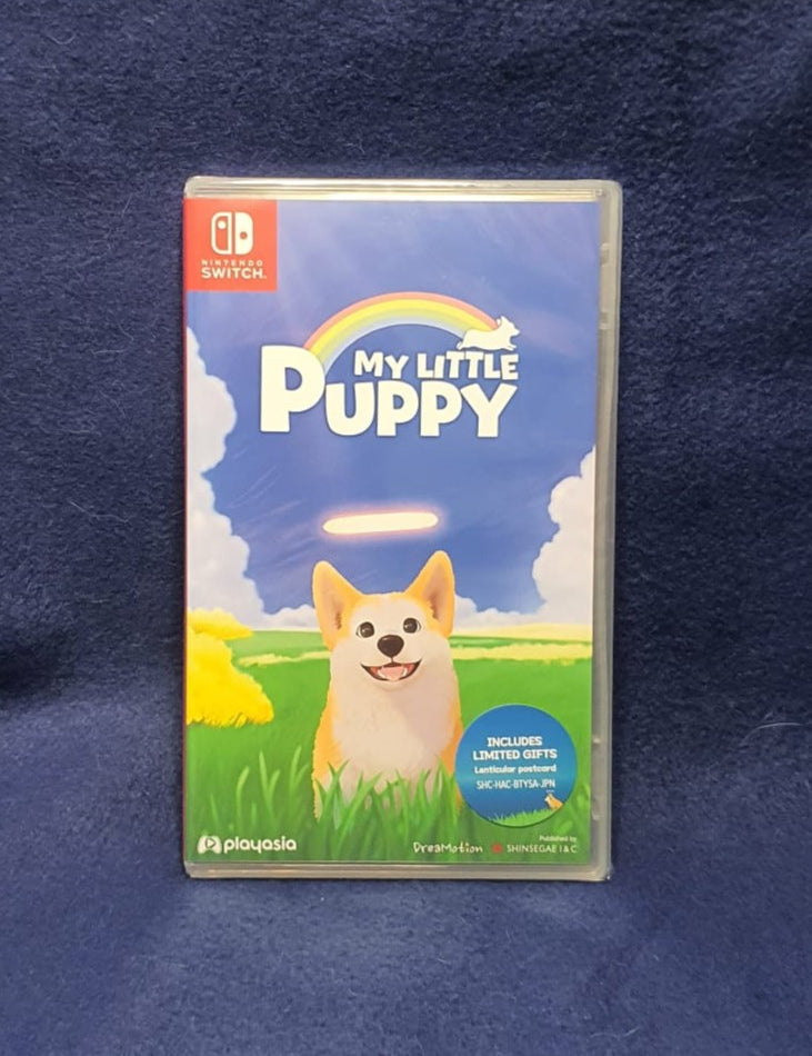 Nintendo Switch game case for 'My Little Puppy' on a dark blue textured fabric background. The cover art features a cute Shiba Inu puppy in a grassy field under a blue sky with a rainbow.